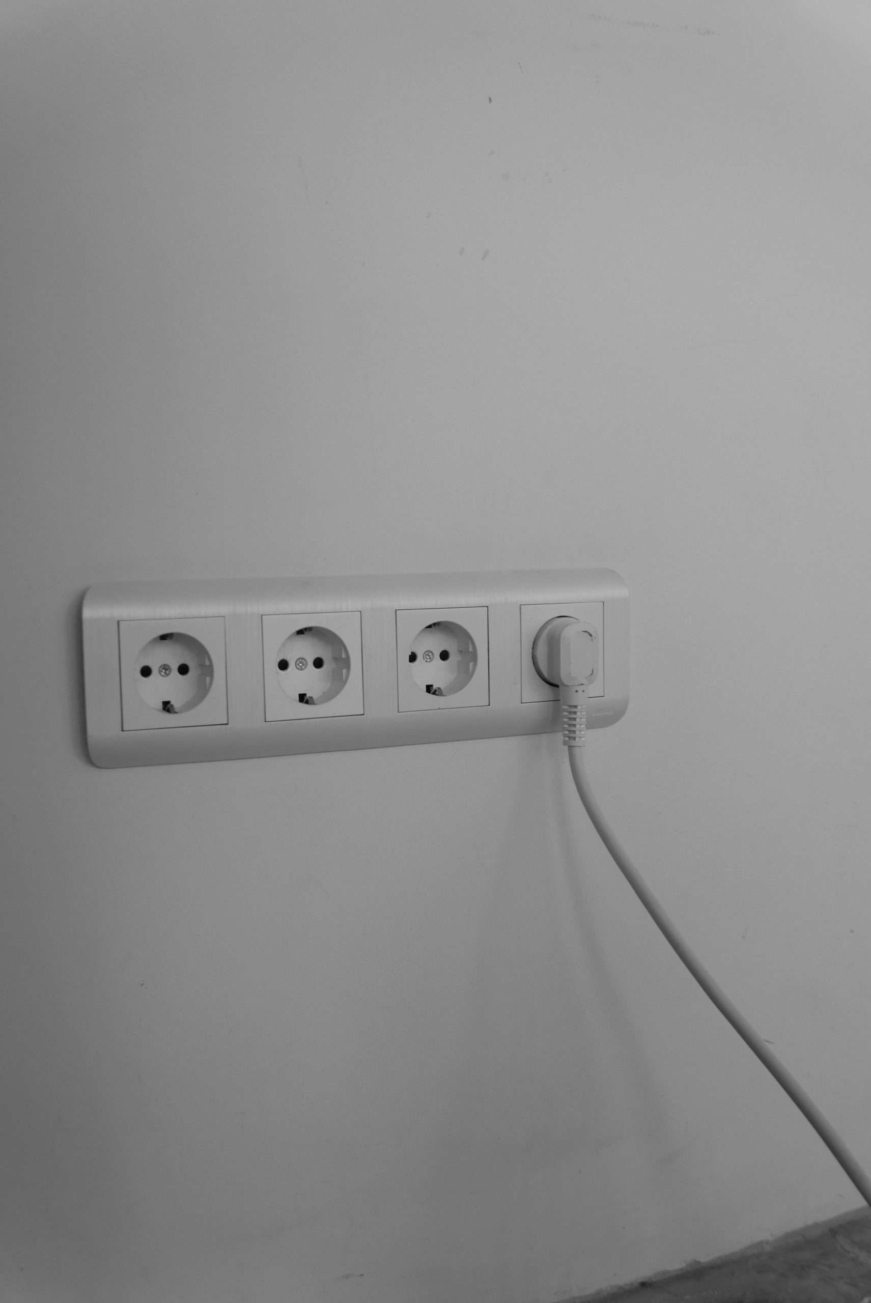 Une prise murale épurée et minimaliste avec une seule fiche branchée, mettant en valeur un design d'intérieur moderne.