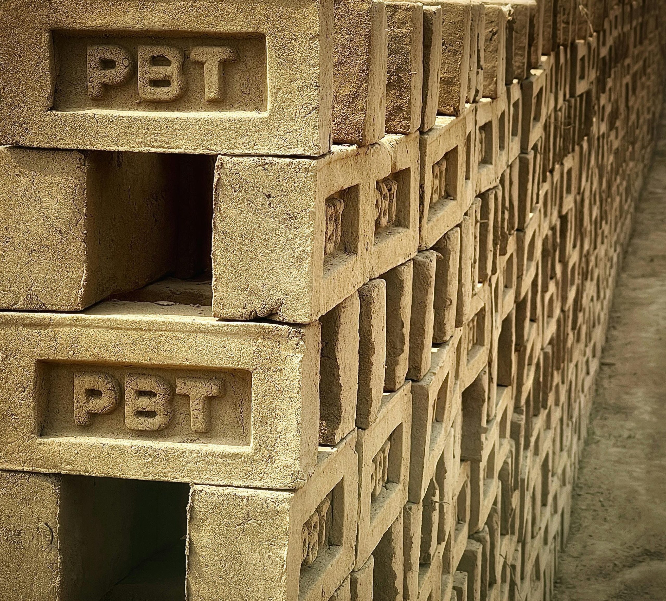 Close-up de briques en béton empilées avec l'inscription PBT, mettant en valeur un matériau industriel.