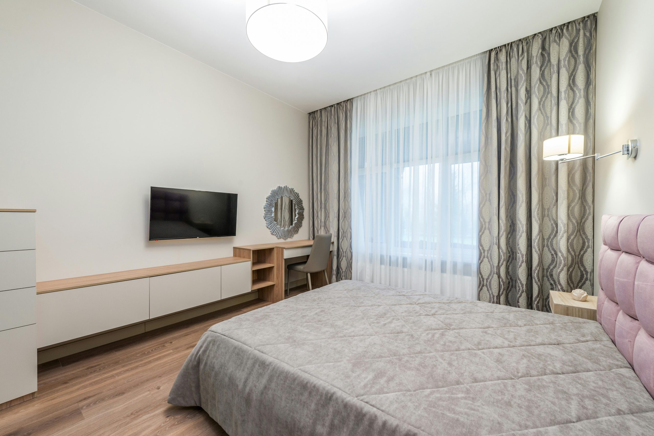Spacieuse chambre moderne avec une décoration minimaliste comprenant un lit, une télévision et des meubles élégants.