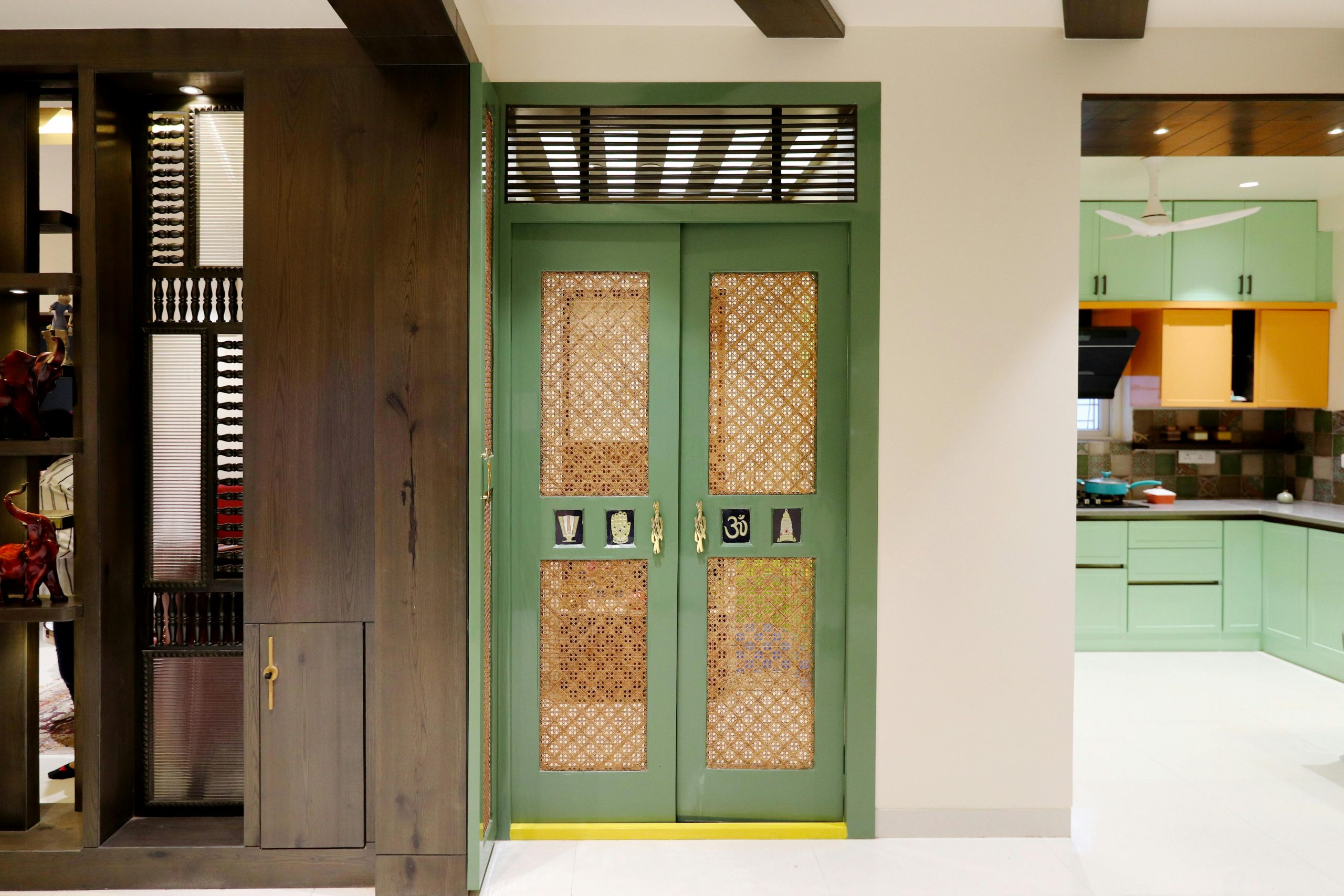Élégante entrée verte avec des motifs de treillis complexes, menant à une cuisine moderne bien éclairée.
