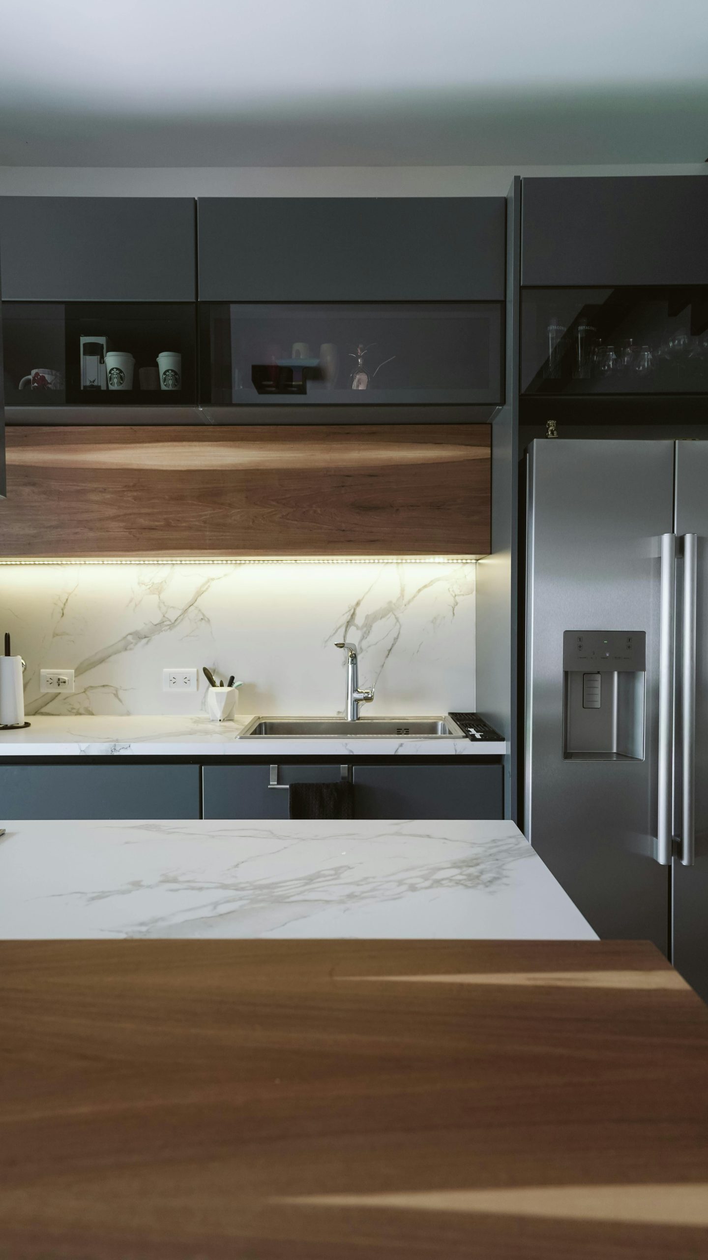 Stylish modern kitchen featuring sleek appliances and marble countertops. Cuisine moderne élégante avec appareils épurés et plans de travail en marbre.