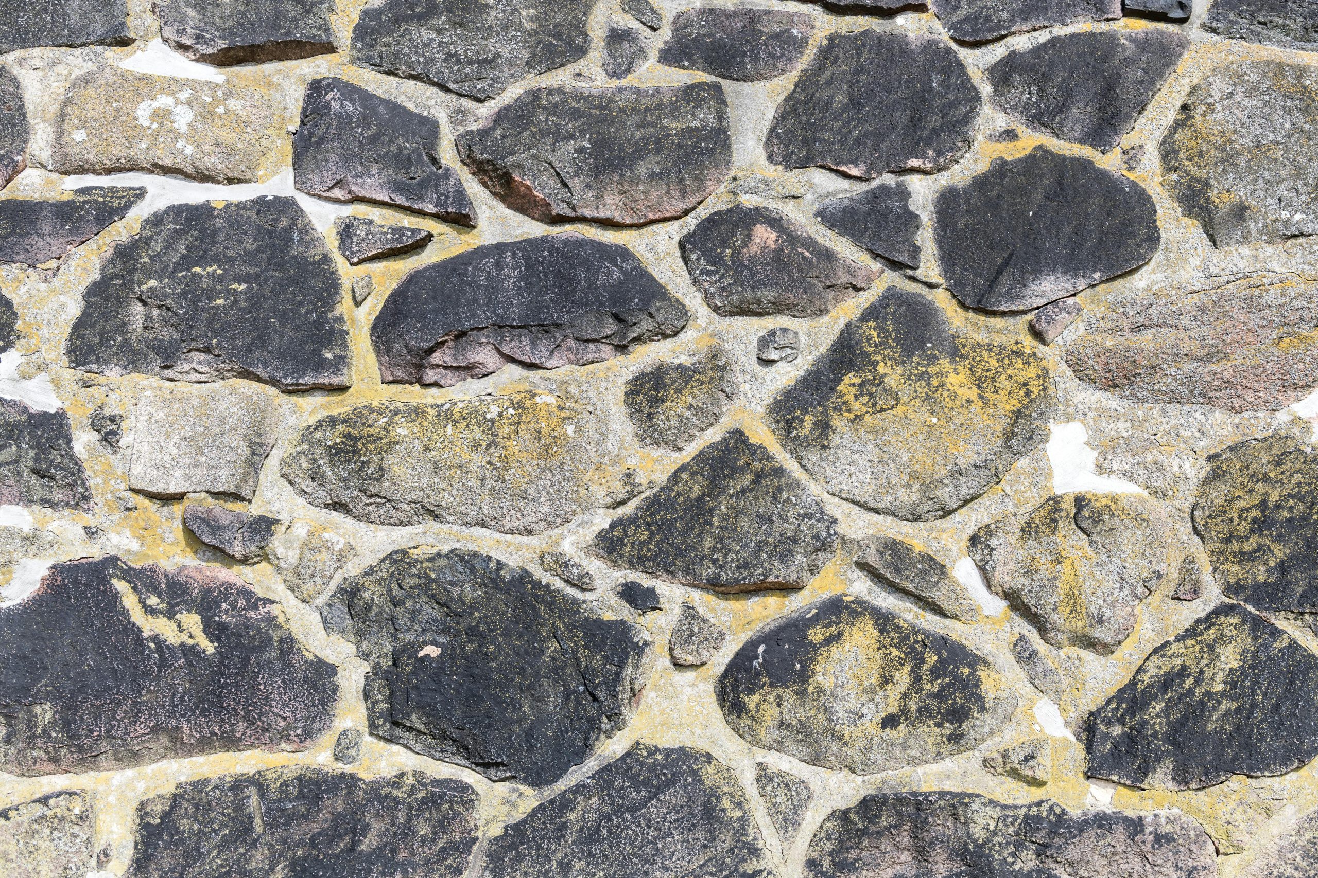 Close-up d'un mur de maçonnerie en pierre ancienne mettant en valeur les textures et motifs naturels de la roche.