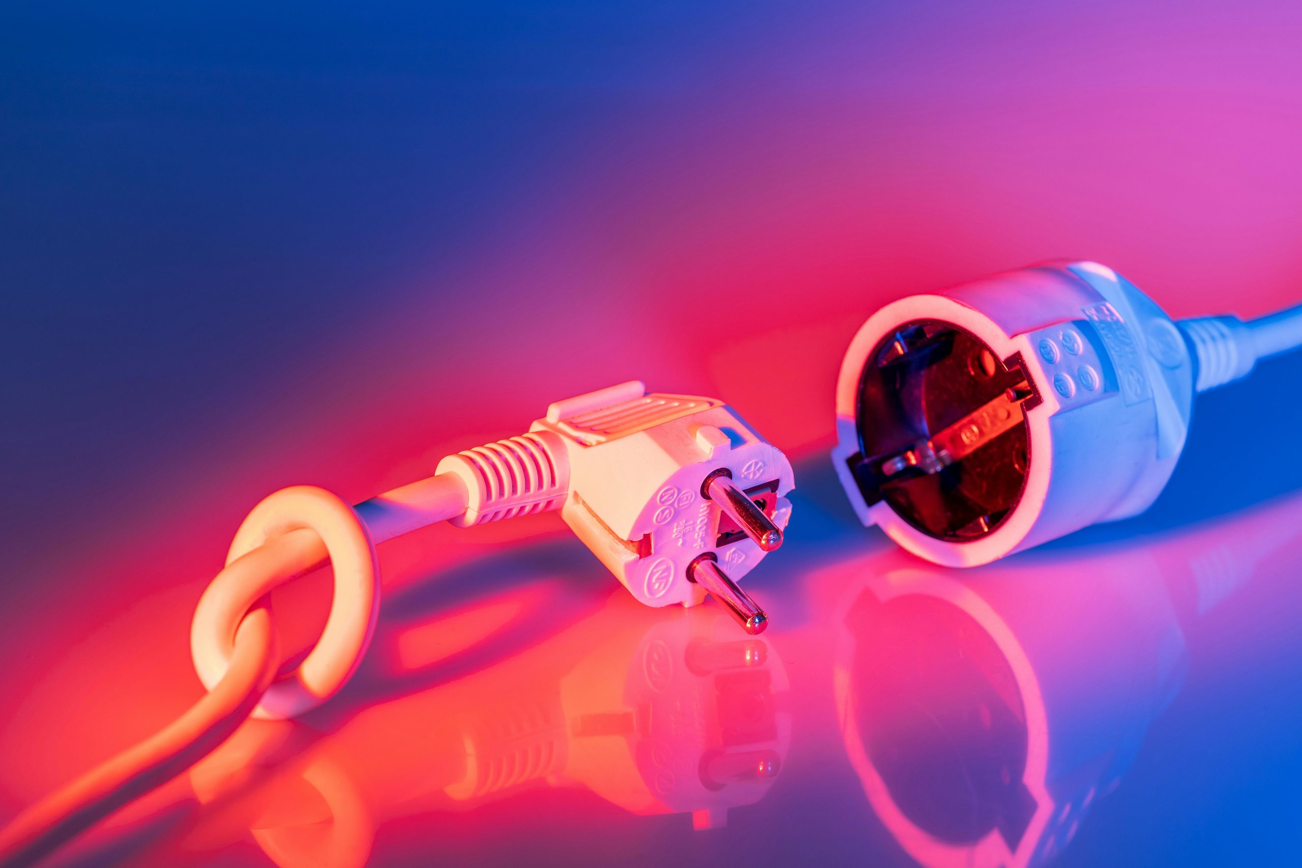 Gros plan d'une prise électrique et d'une fiche avec un éclairage vibrant, illustrant les concepts de technologie et d'énergie.