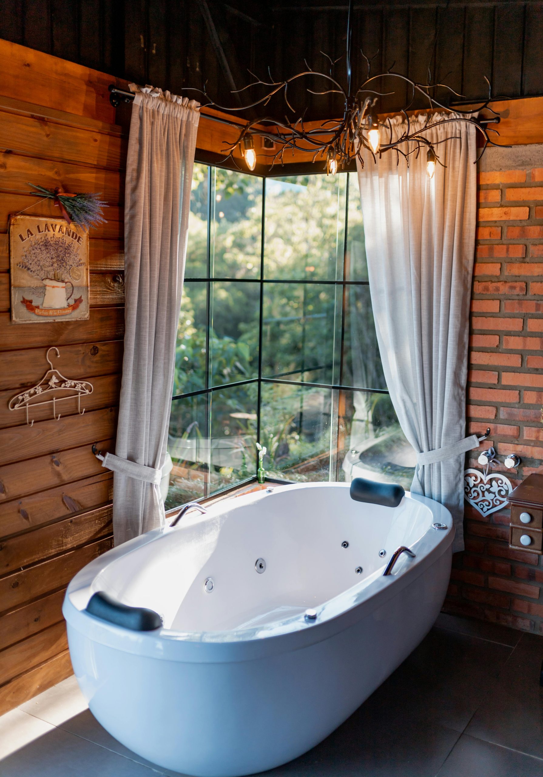 Charming rustic bathroom interior featuring a freestanding bathtub by a large window. Intérieur de salle de bain rustique charmant avec une baignoire indépendante près d'une grande fenêtre.