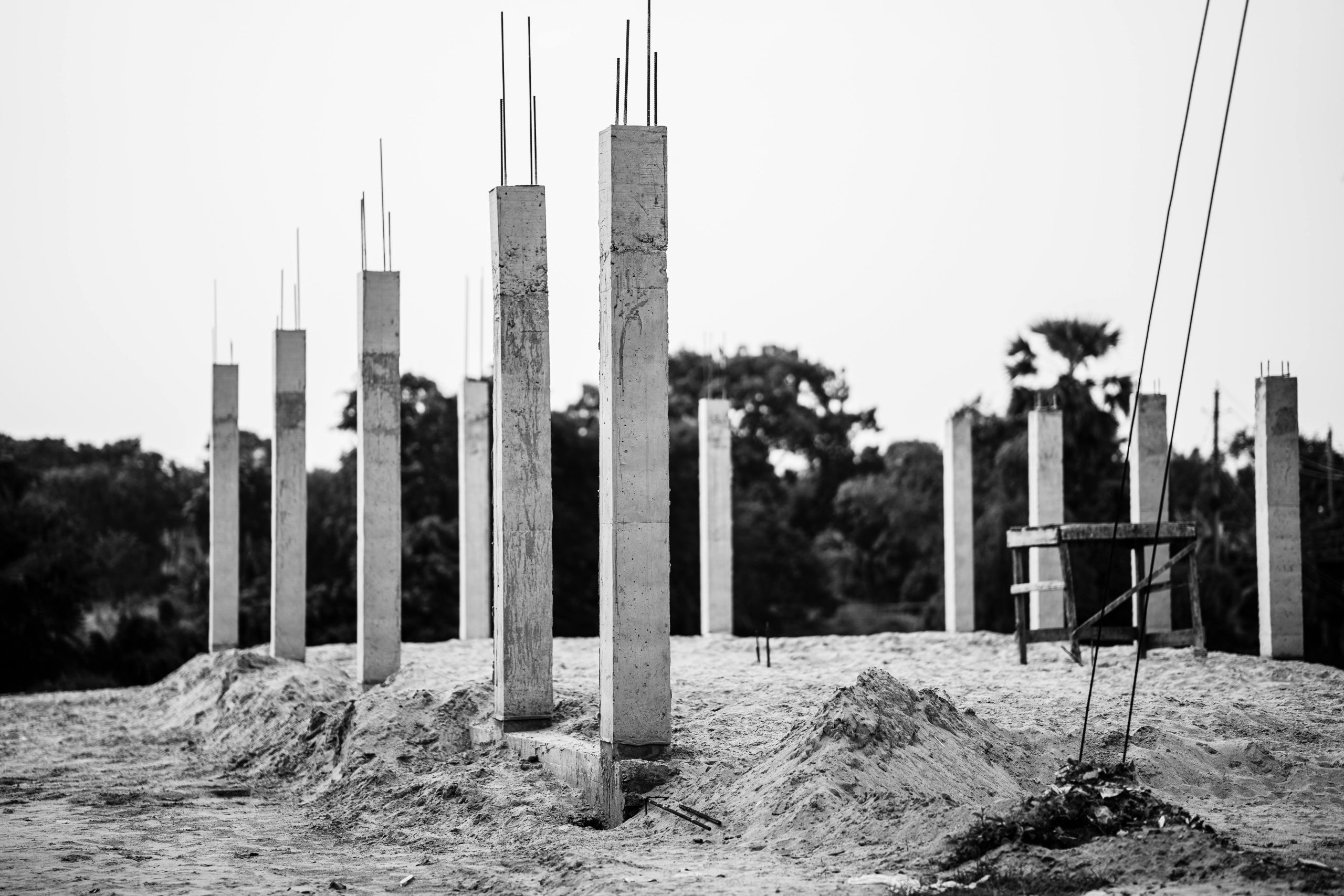 Black and white image of concrete pillars at an unfinished construction site in Faridpur, Bangladesh. Image en noir et blanc de piliers en béton sur un chantier de construction inachevé à Faridpur, Bangladesh.
