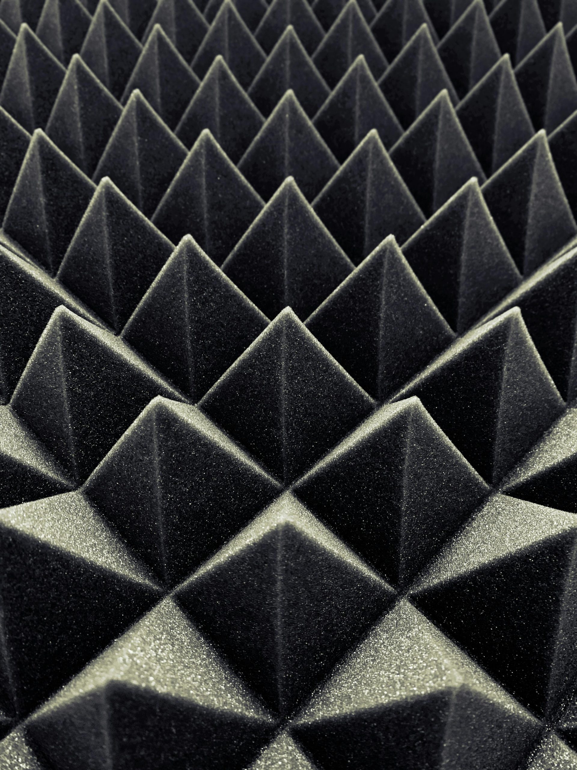 Textured black acoustic foam panels create a striking geometric pattern. Panneaux de mousse acoustique noire texturée créant un motif géométrique frappant.