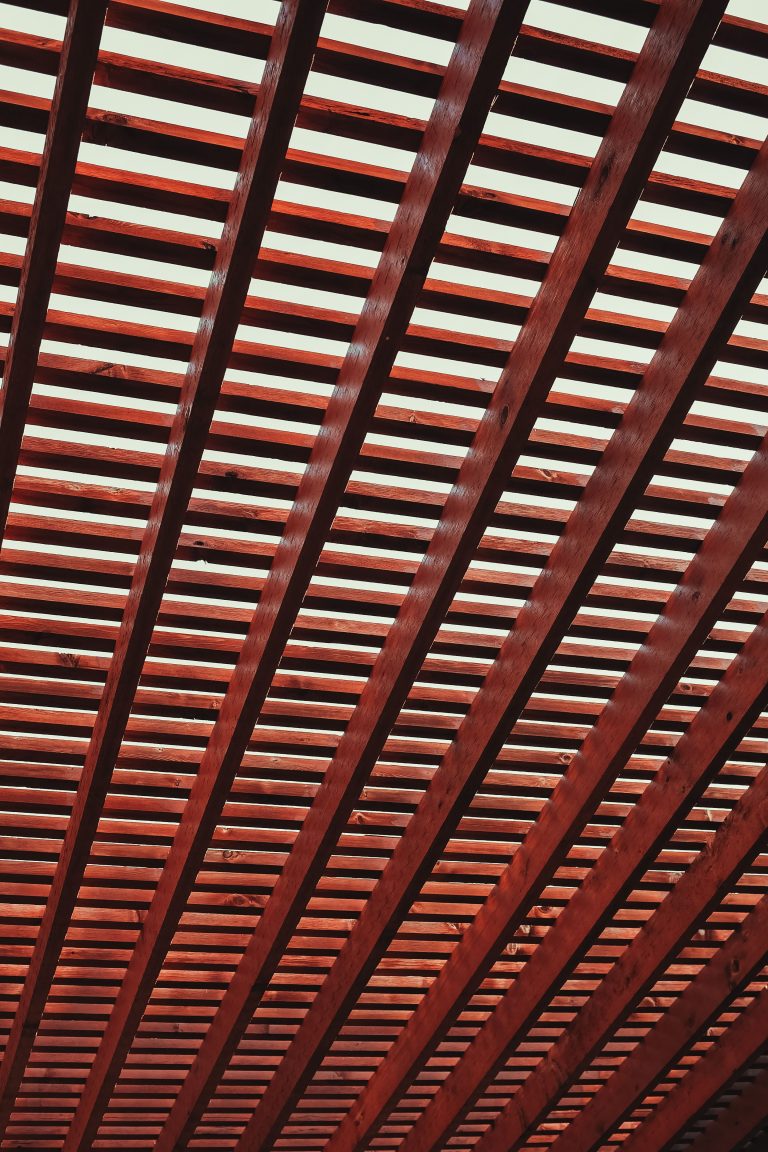 An intricate design featuring diagonal wooden beams creating a geometric ceiling pattern. Un design complexe présentant des poutres en bois diagonales créant un motif de plafond géométrique.