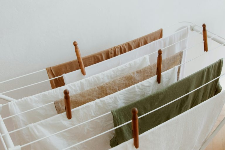 A minimalist image of clothes drying on a rack indoors, showcasing neatness and order. Une image minimaliste de vêtements qui sèchent sur un séchoir à l'intérieur, mettant en avant la propreté et l'ordre.