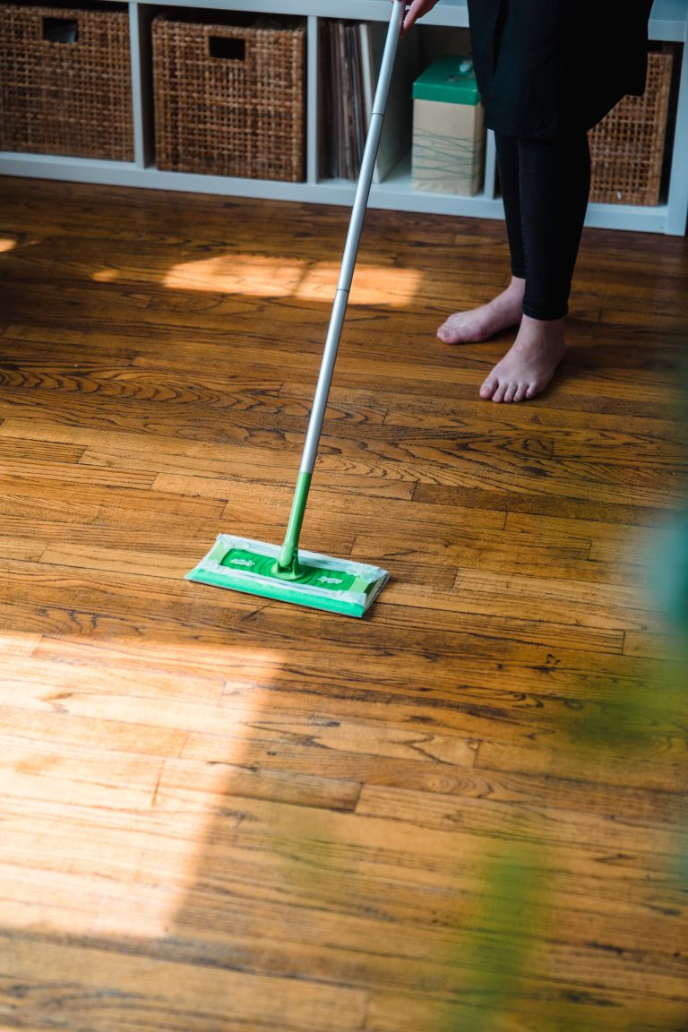 Modern cleaning service image featuring a person with a green mop on a wooden floor indoors. Image de service de nettoyage moderne montrant une personne avec une serpillière verte sur un sol en bois à l'intérieur.
