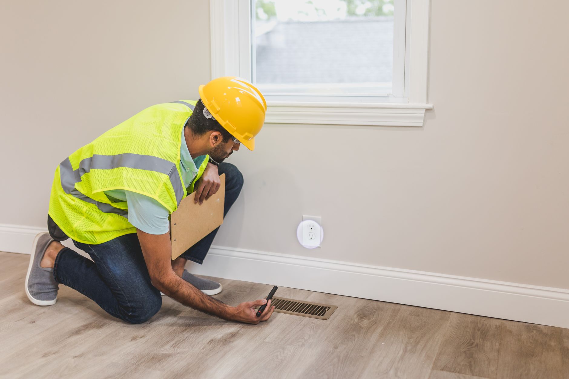 Ouvrier inspectant une bouche d'aeration avant travaux de renovation
